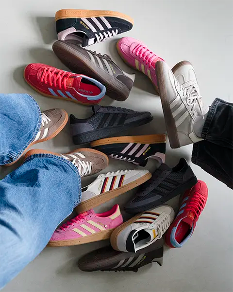 A circle of colorful adidas Handball Spezial sneakers worn by people, featuring red, pink, black, brown, and white designs, creating a vibrant and casual mood.